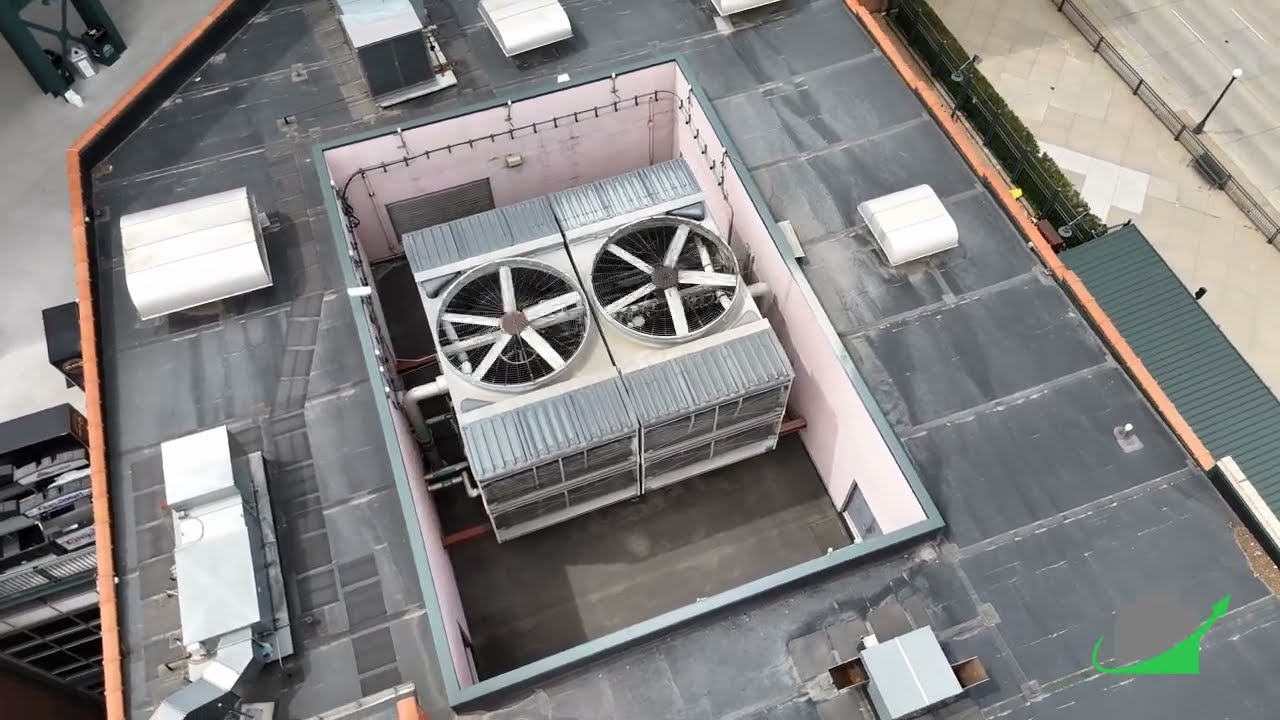 Aerial view of two rooftop package cooling towers with exposed fans, sitting in a screened well on a commercial building roof.